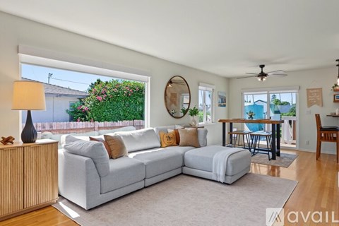 A living room with a white couch and a round mirror on the wall.