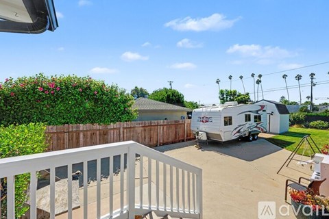 A white Avalon balcony overlooks a yard with a pool and a trailer.