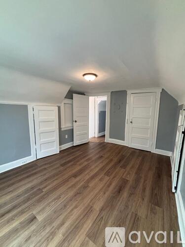 A room with wooden flooring and white walls.
