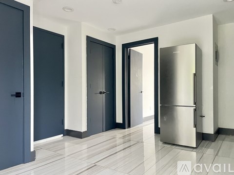A kitchen with a refrigerator, cabinets, and a door.