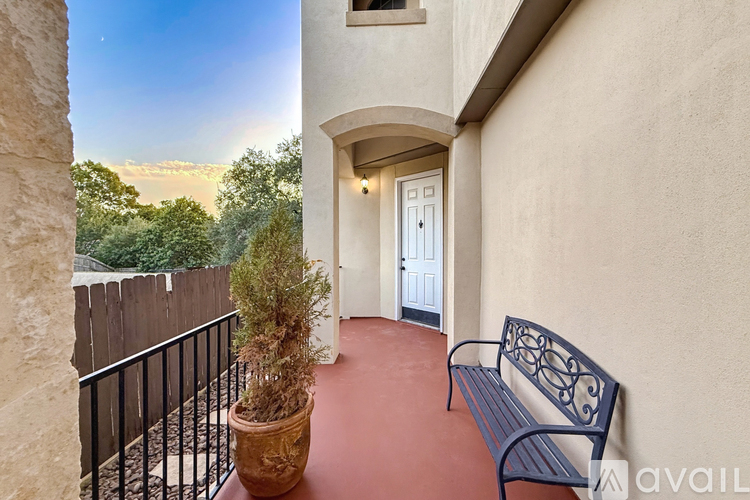 A balcony with a bench and a potted plant.