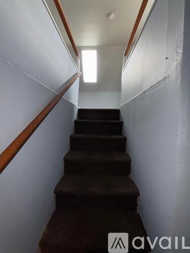 A staircase with a brown carpeted runner and wooden balusters.