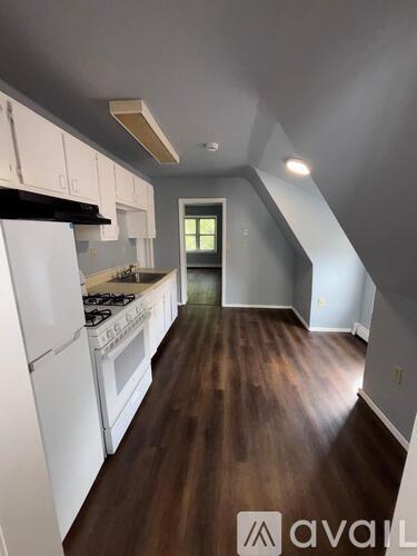 A kitchen with white appliances and wood floors.