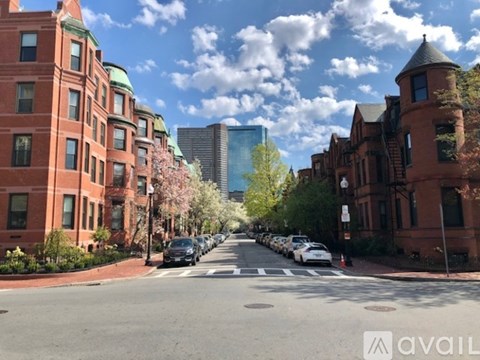 A street lined with red brick buildings and cars parked on the side.