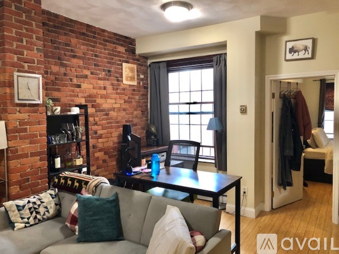 A living room with a grey couch and a brick wall.