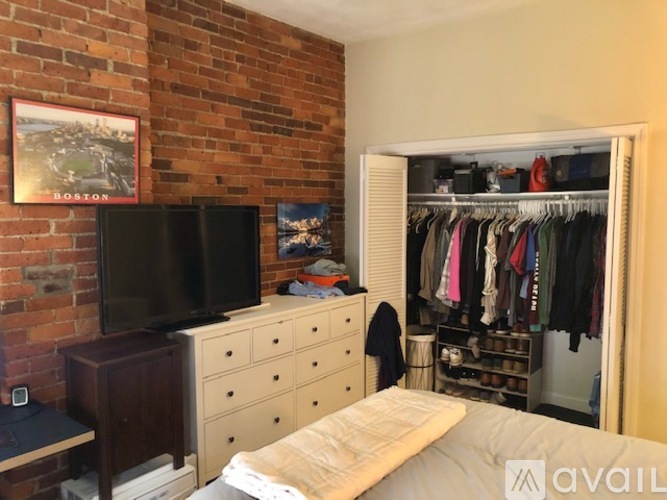 A bedroom with a brick wall and a bed with a white pillow.