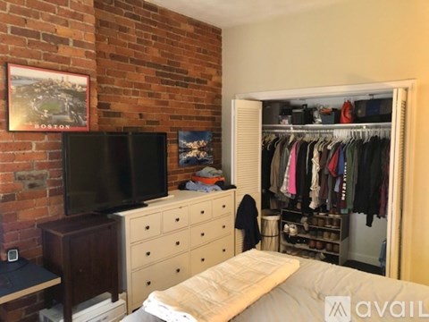 A bedroom with a brick wall and a bed with a white pillow.