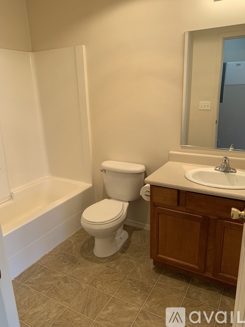 A white toilet sits in a bathroom next to a bathtub.