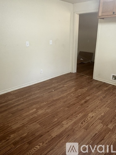A room with wooden flooring and a doorway leading to another room.