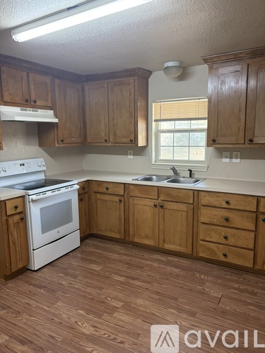 A kitchen with wooden cabinets and a white stove top oven.