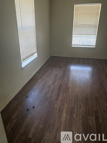A room with wooden flooring and a window with blinds.