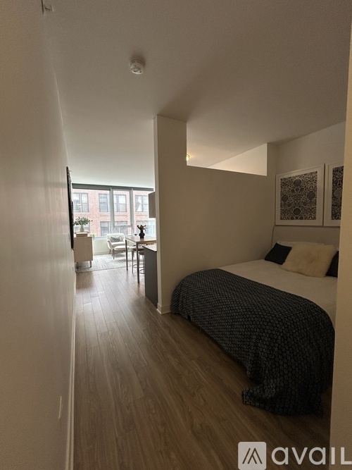 A bedroom with a bed and a table in front of a window.