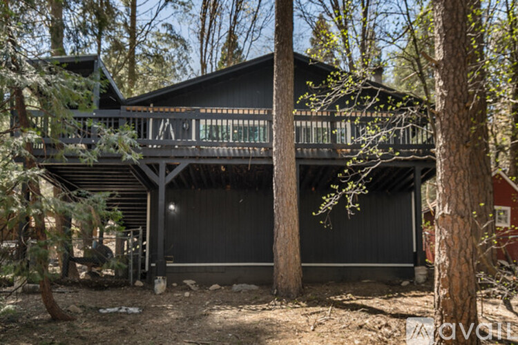 A black house with a balcony surrounded by trees.