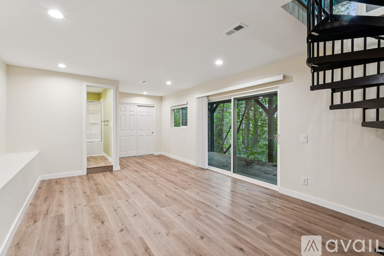 A spacious room with wooden flooring and a staircase on the right side.