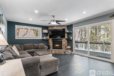 A living room with a grey couch and a fireplace.