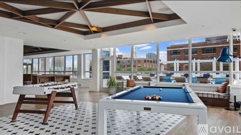 A billiard table is in the middle of a room with a pool table and a view of the city.