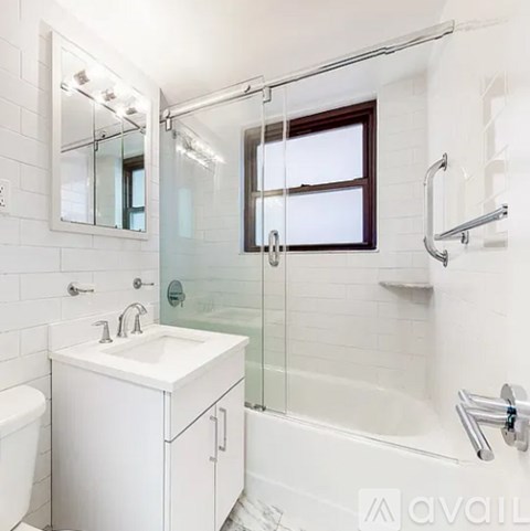 A white bathroom with a sink, mirror, and bathtub.
