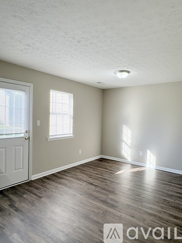 A room with a door, window, and wooden flooring.