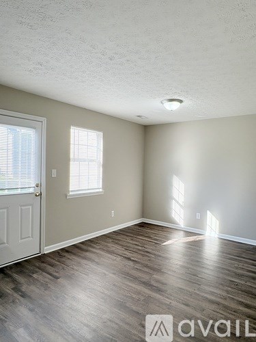 A room with a door, window, and wooden flooring.