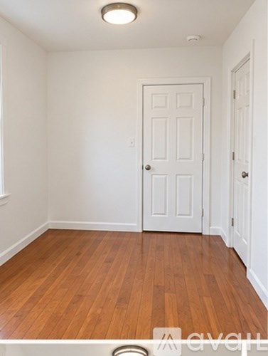 A room with a white door and wooden floors.