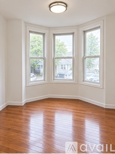 A room with wooden floors and three windows.