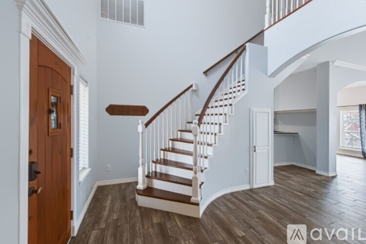A wooden staircase with white railings leads to the upper floor of a house.