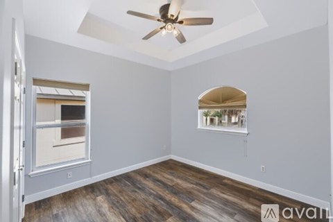 A room with a ceiling fan and a window with a view of a building outside.