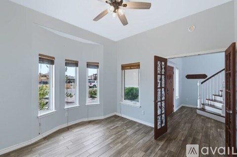 A room with a ceiling fan and wooden flooring.
