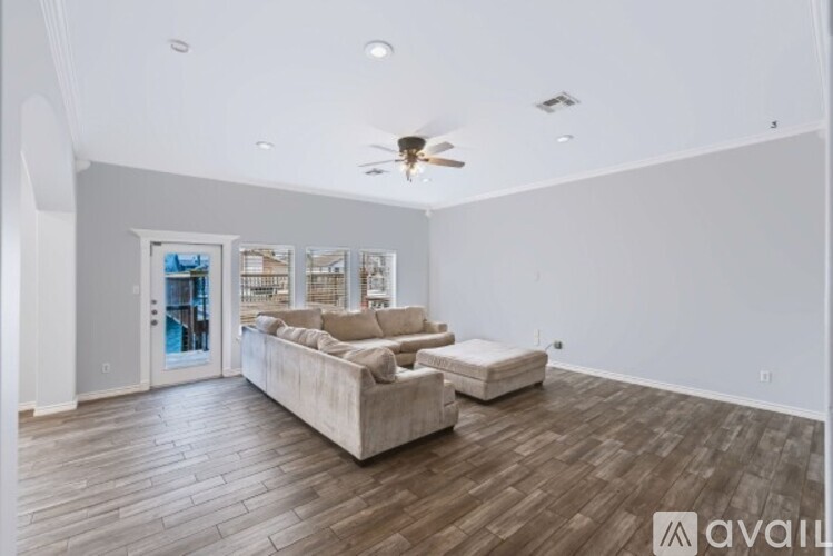 A spacious living room with a couch and a ceiling fan.