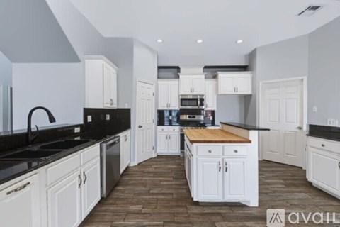 A kitchen with white cabinets and black countertops.