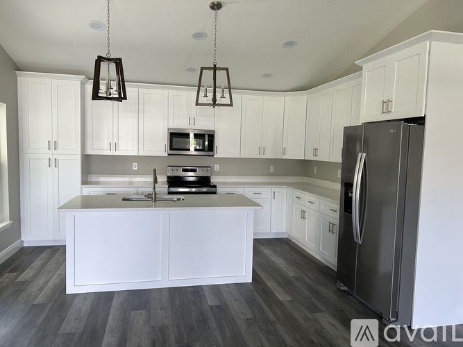 A modern kitchen with white cabinets and a black refrigerator.