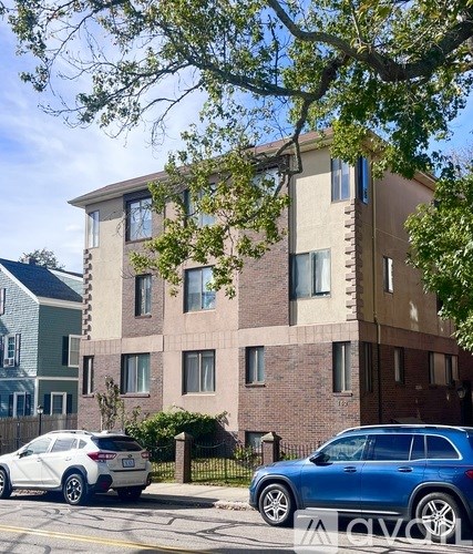 A blue car is parked in front of a multi-story building.