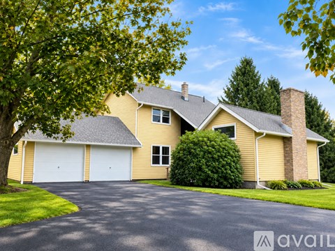 A house with a garage and a tree in front.
