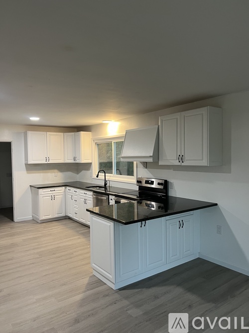 A kitchen with white cabinets and a black countertop.