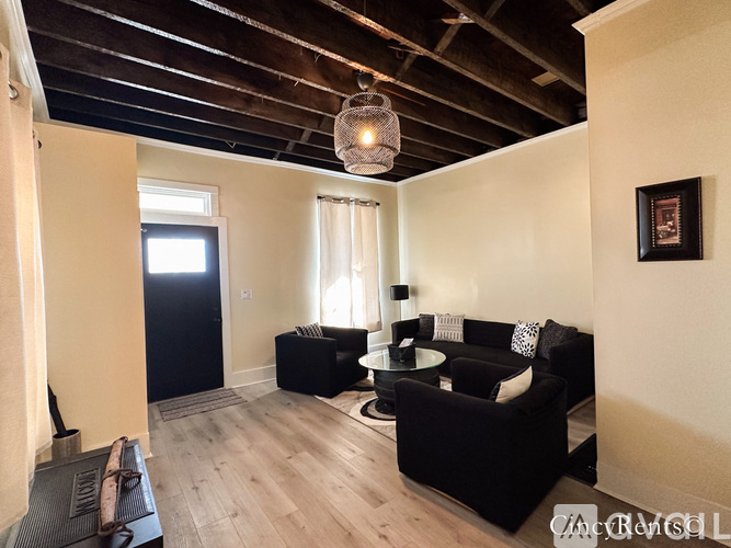 A living room with black furniture and a wooden ceiling.