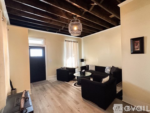 A living room with black furniture and a wooden ceiling.