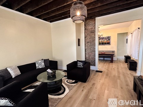 A living room with a black couch and a glass table.