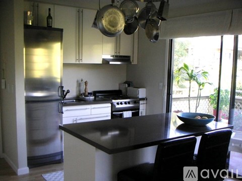 A kitchen with a black counter top and a stainless steel refrigerator.