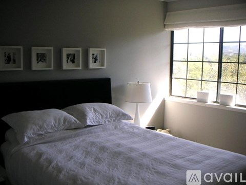 A bedroom with a large bed and a window overlooking a green landscape.