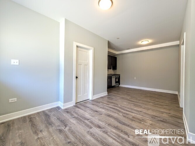 A spacious room with a door and a light switch on the wall.