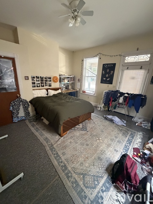 A bedroom with a bed, a ceiling fan, and a rug on the floor.