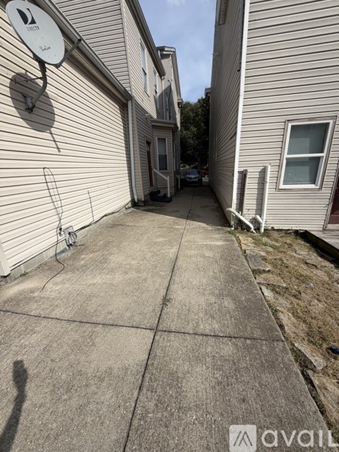 A concrete walkway leads to a door in a residential area.