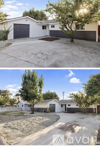 A two-story house with a garage and a tree in front.