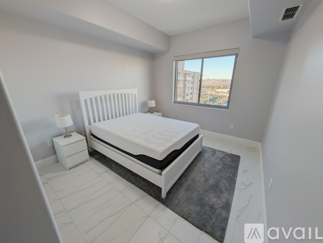 A bedroom with a large bed and a window overlooking a cityscape.