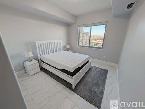 A bedroom with a large bed and a window overlooking a cityscape.