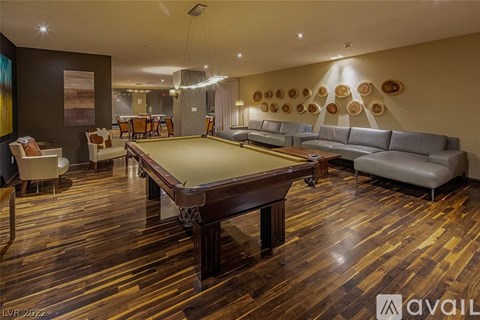 A pool table is in the middle of a room with a couch and chairs.