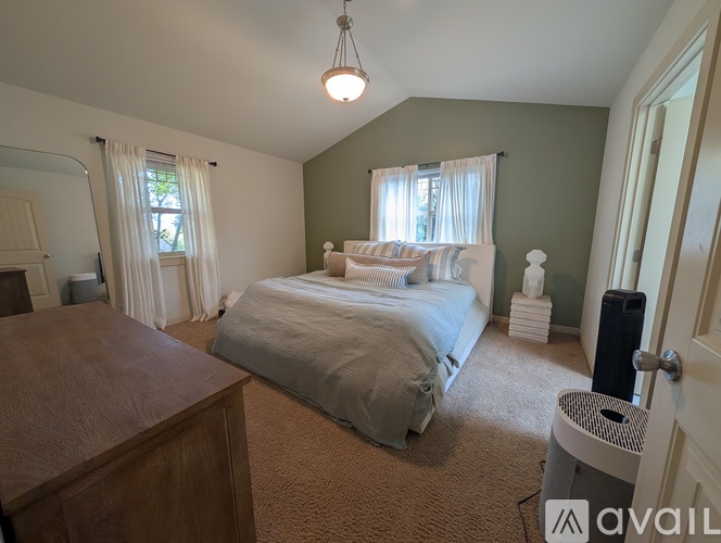 A bedroom with a bed, nightstand, and window with curtains.
