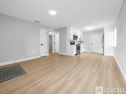 A spacious living room with wooden flooring and white walls.