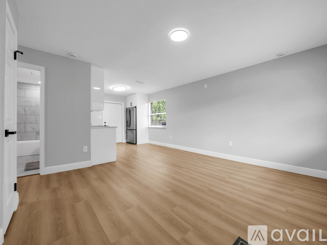 A spacious room with wooden flooring and white walls.