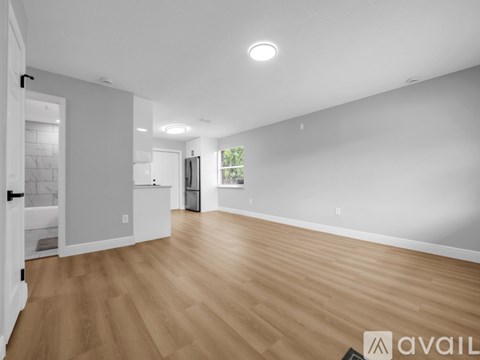 A spacious room with wooden flooring and white walls.